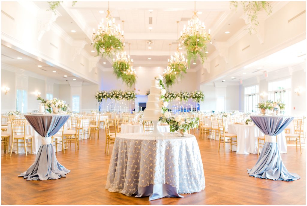 large ballroom reception decorated with flowers and cake