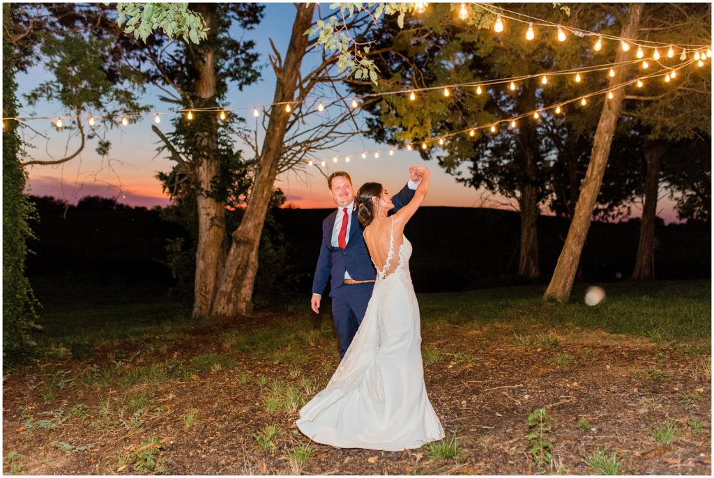 Bride and groom twirling under the lights at sunset at the ruby cora in clarksville tennessee