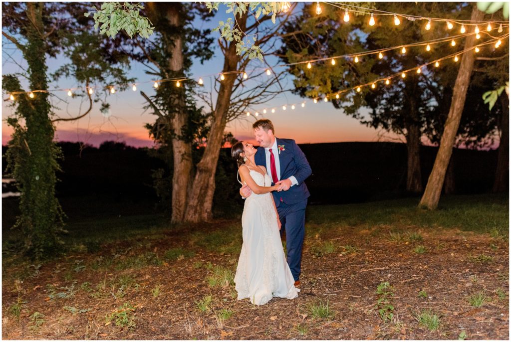 Bride and groom twirling under the lights at sunset