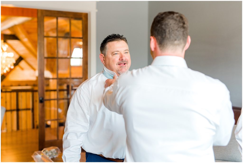 Groom helping father in law get ready at the Carolina Barn, Spring Lake NC | by Kaitlyn Blake Photography